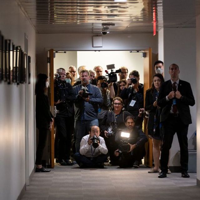 Eine Gruppe von Journalistinnen und Journalisten sitzt und steht am Ende eines Ganges.