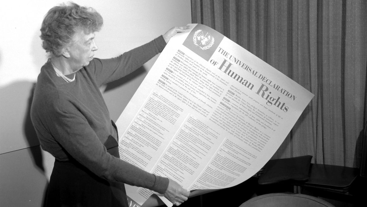 Eleanor Roosevelt hält schräg ein Plakat.