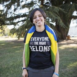 Die ehemals staatenlose Aktivistin Maha Mamo, kurz nachdem sie ihren brasilianischen Pass erhalten hat Eine Frau lächelt breit in die Kamera, um die Schultern hat sie eine brasilianische Flagge