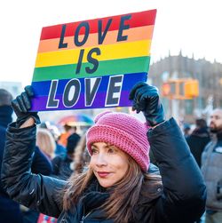 Eine Frau hält ein Plakat in Regenbogenfarben mit der Botschaft "Love is love".