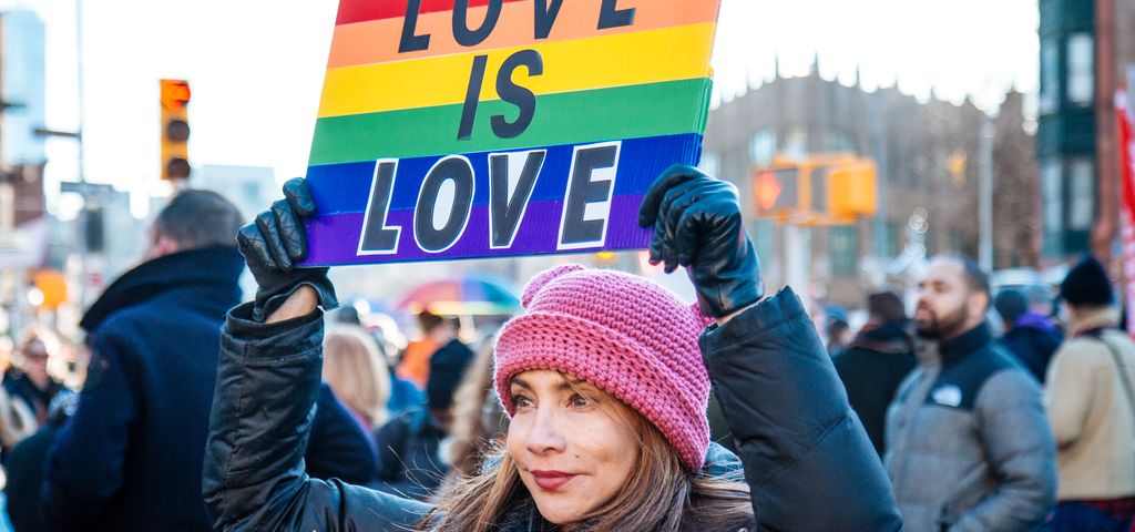 Eine Frau hält ein Plakat in Regenbogenfarben mit der Botschaft "Love is love".
