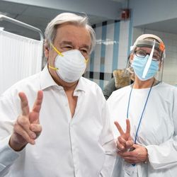 UN-Generalsekretär Antonió Guterres, ein älterer weißer Mann, erhält seine erste Impfung und zeigt das Victory-Zeichen. 