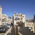 Die große Mehrheit der Geflüchteten lebt nicht in Camps, sondern in Städten wie Amman Eine Straßenansicht von weißen Häusern, in der Ferne das Graffiti eines Frauengesichts
