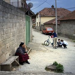 Eine alte Frau und spielende Kinder auf einer Straße in Rahovec (Orahovac) in Kosovo, wo besonders Angehörige von Minderheiten leben.