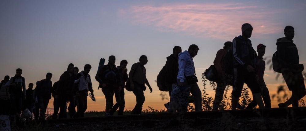 Ein Treck von Flüchtlingen im Sonnenuntergang.